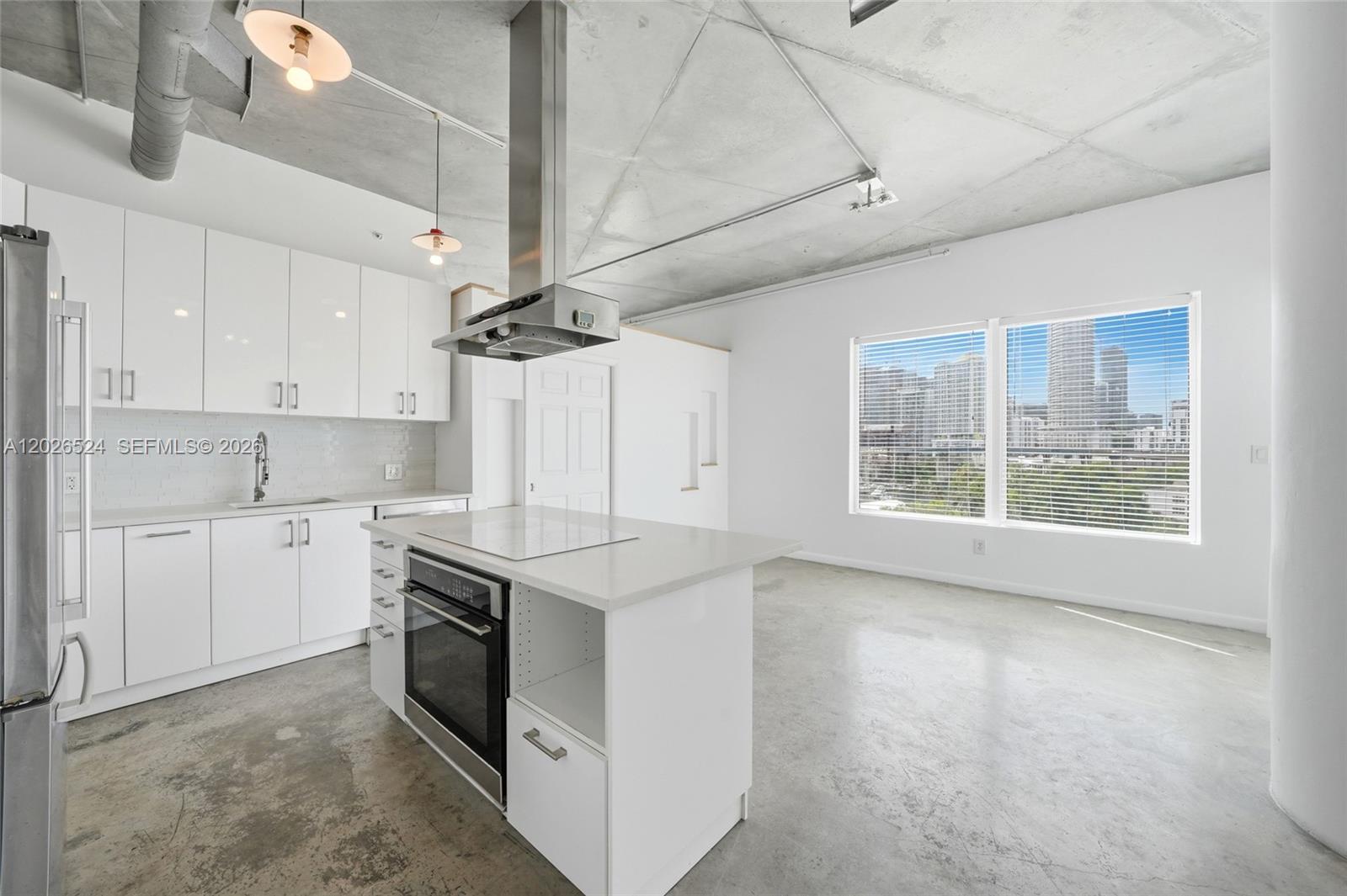 A modern kitchen features white cabinets, a central island, and exposed concrete ceilings and floors — 10 SW South River Dr # 804, Miami FL 33130, MIAMI, FL