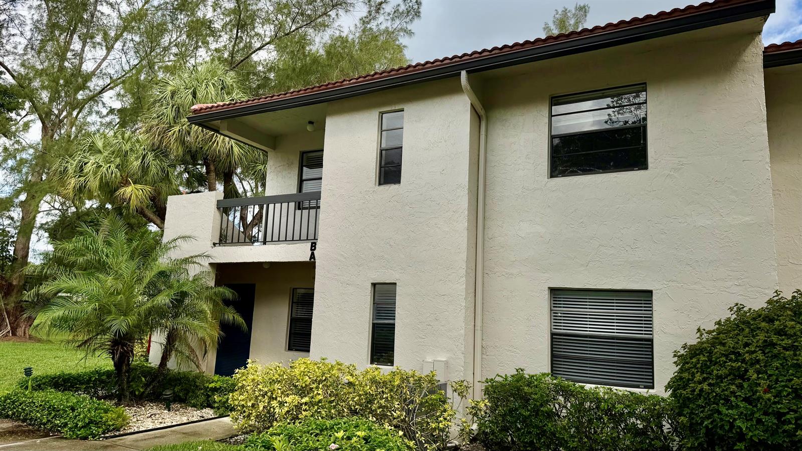 A two-story stucco apartment building features a second-floor balcony and surrounding landscaping — 21695 Tall Palm Circle # 4a, Boca Raton FL 33433, BOCA RATON, FL