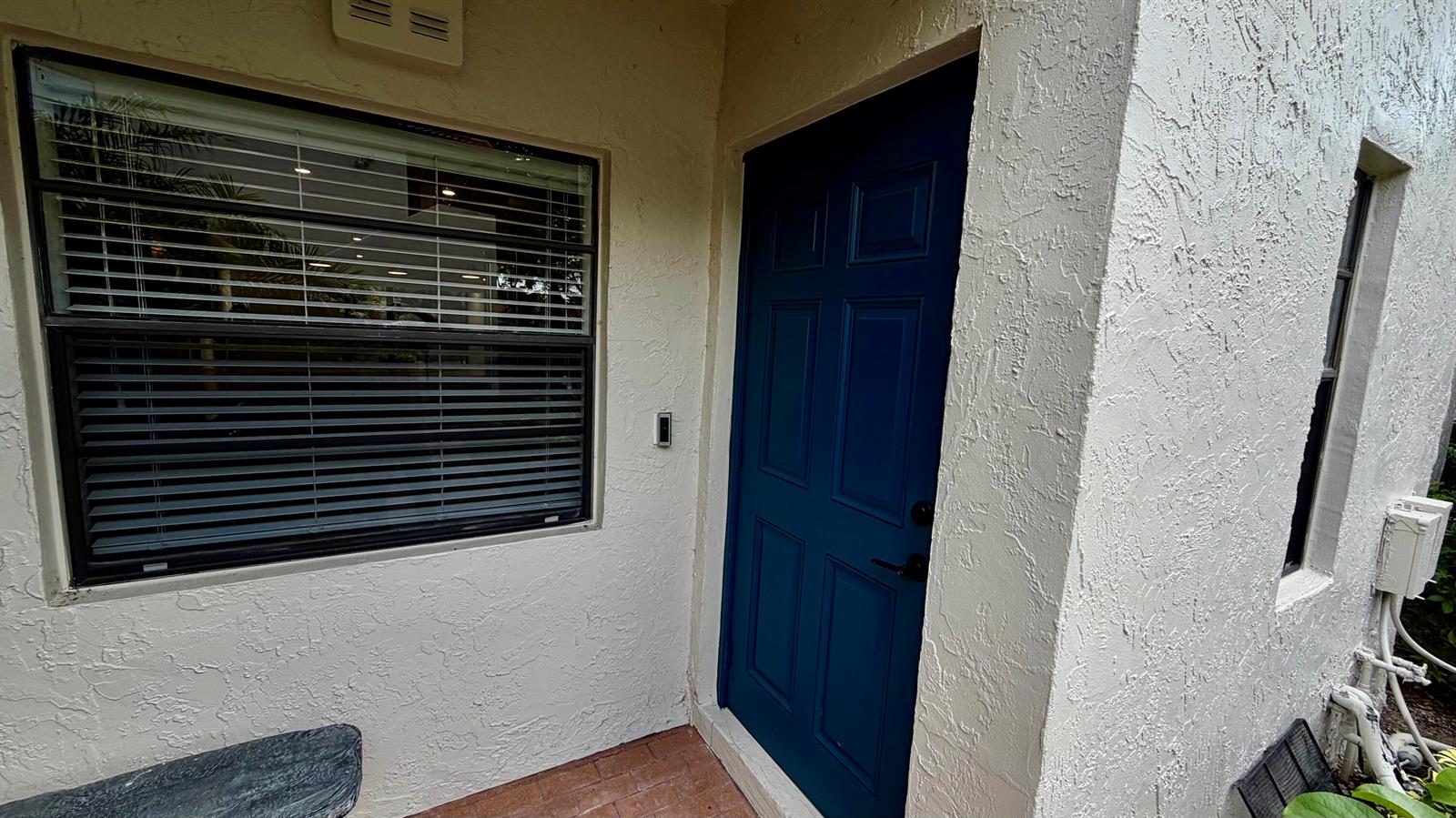A blue front door sits next to a window with closed blinds on a stucco wall — 21695 Tall Palm Circle # 4a, Boca Raton FL 33433, BOCA RATON, FL