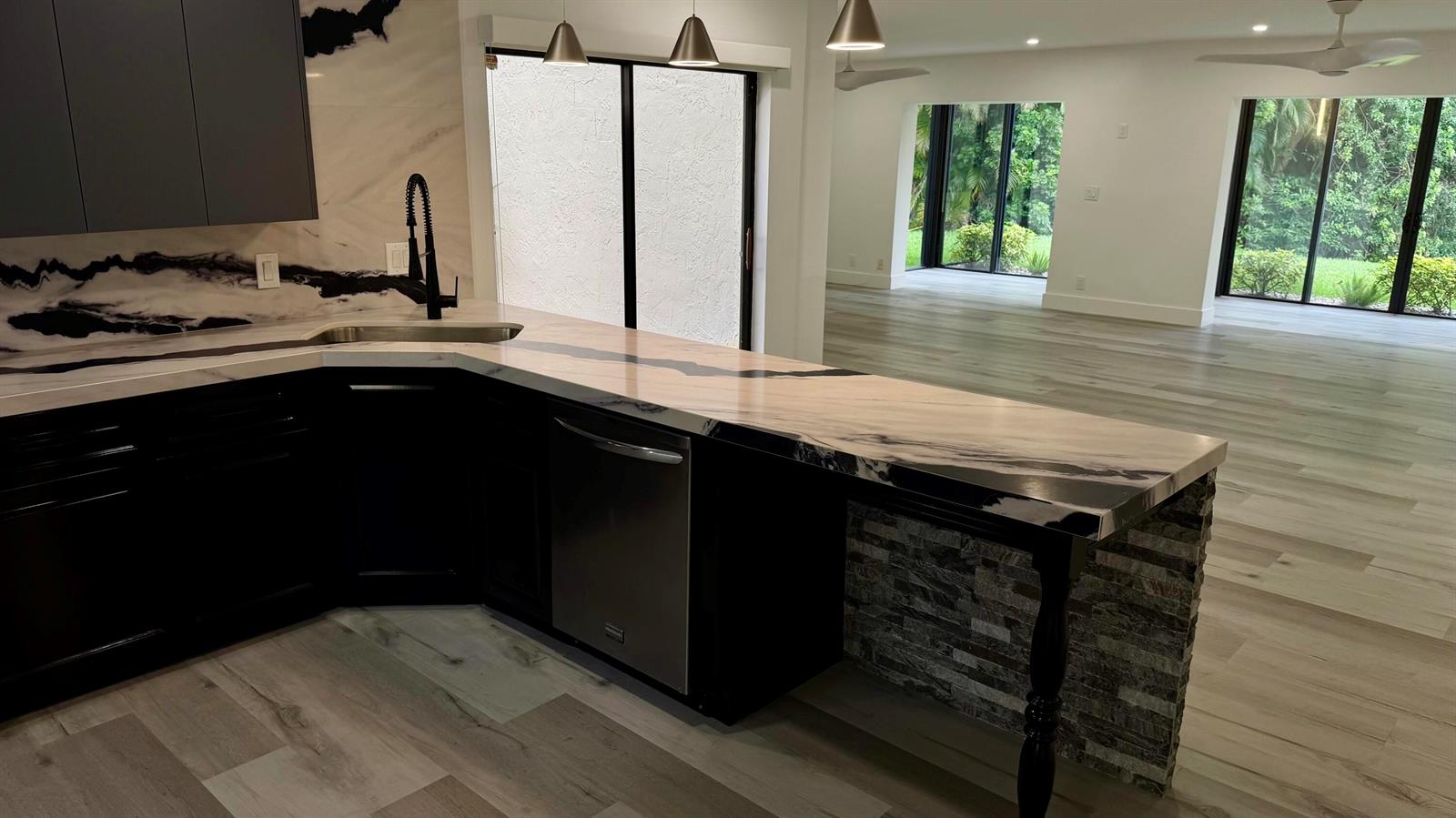 A kitchen with black cabinets, a marble-patterned countertop, and a stone-accented breakfast bar — 21695 Tall Palm Circle # 4a, Boca Raton FL 33433, BOCA RATON, FL