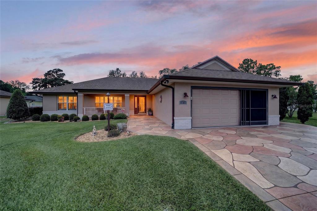 A single-story house with a tan stucco exterior, a stone-patterned driveway, and a garage — 16364 SE 89TH TERRACE, SUMMERFIELD, FL