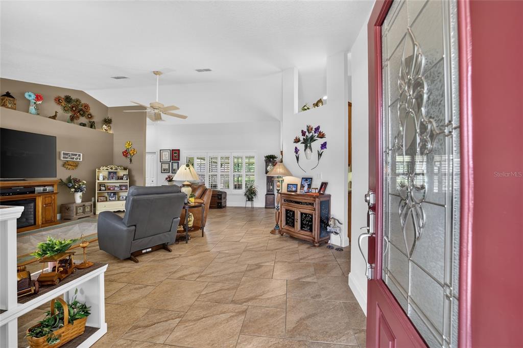 A view from an entryway into a living room with tile floors and vaulted ceilings — 16364 SE 89TH TERRACE, SUMMERFIELD, FL