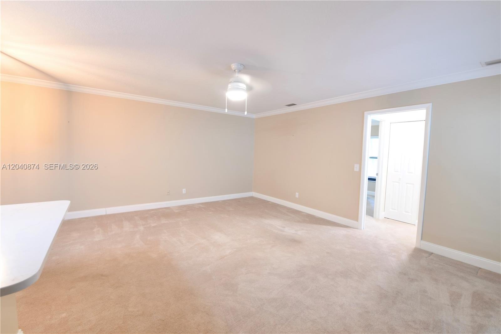 An empty room features beige walls, tan carpeting, a ceiling fan, and a doorway — 1188 Breezy Way # 6D, Sebastian FL 32958, SEBASTIAN, FL