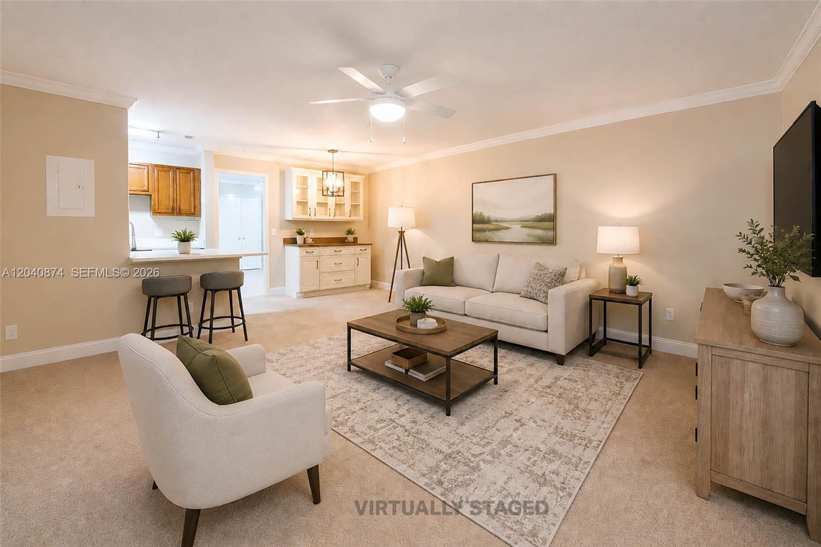 This living room features beige carpeting, a neutral sofa, a coffee table, and a kitchen — 1188 Breezy Way # 6D, Sebastian FL 32958, SEBASTIAN, FL