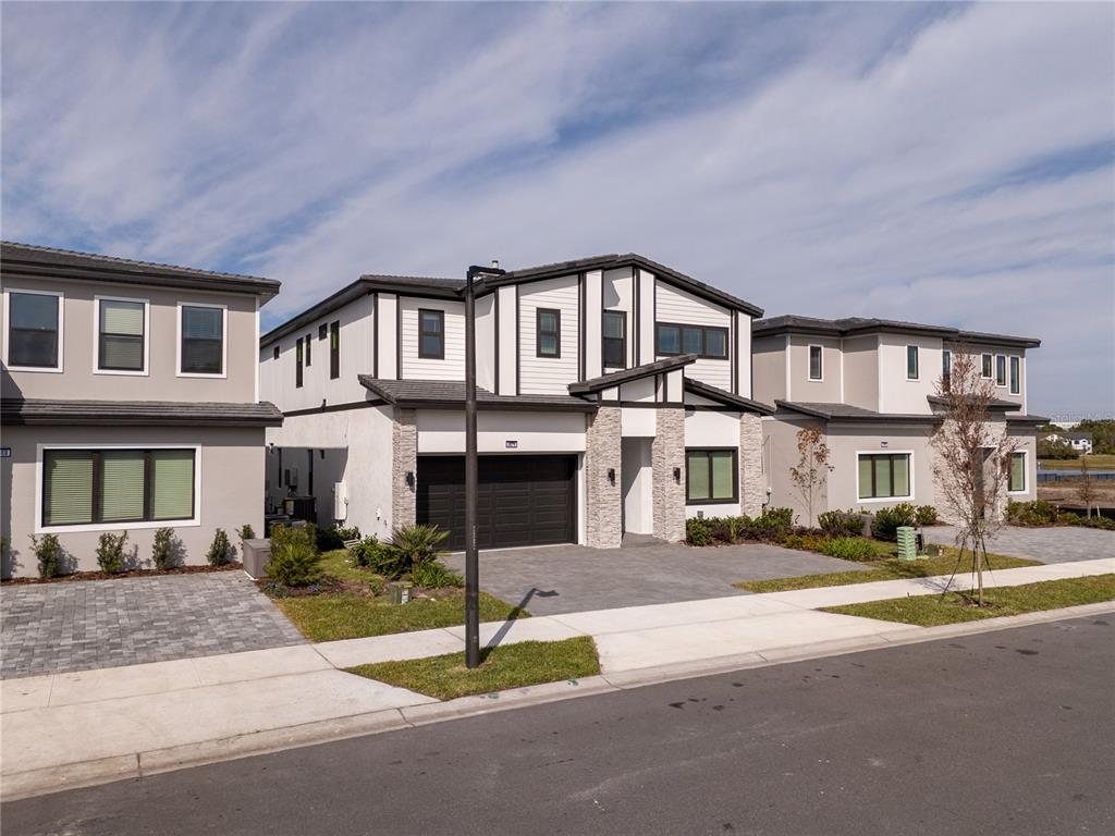 A modern two-story townhouse with a stone-accented facade and a dark two-car garage — 5674 HIGH SEAS DRIVE, ORLANDO, FL
