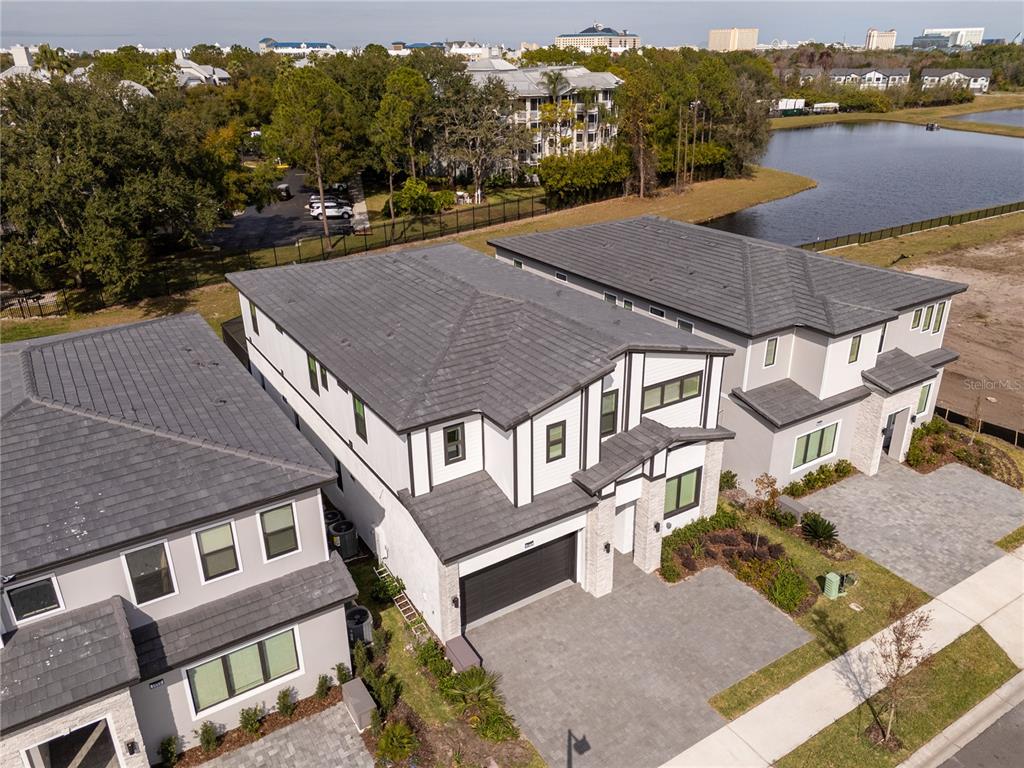 An aerial view shows three modern townhouses with gray tile roofs and paved driveways — 5674 HIGH SEAS DRIVE, ORLANDO, FL