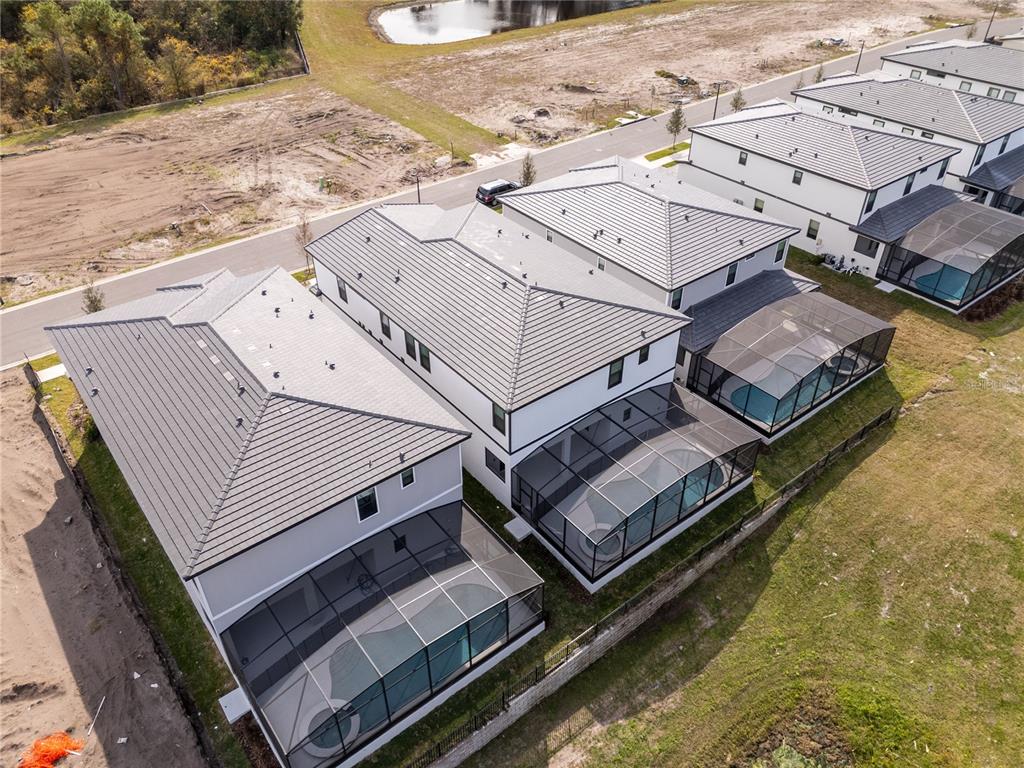 An aerial view shows three modern houses with screened-in pools and dark tiled roofs — 5674 HIGH SEAS DRIVE, ORLANDO, FL