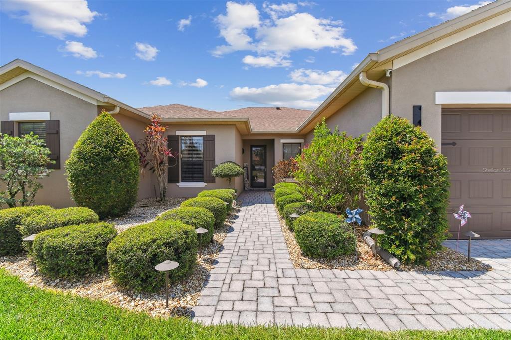 A paved walkway leads to the front entrance of a house with tan stucco siding — 429 VILLA PARK ROAD, KISSIMMEE, FL