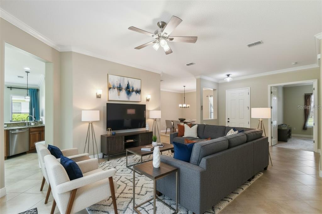 A living room with a gray sectional sofa, two armchairs, and a television on a console — 429 VILLA PARK ROAD, KISSIMMEE, FL