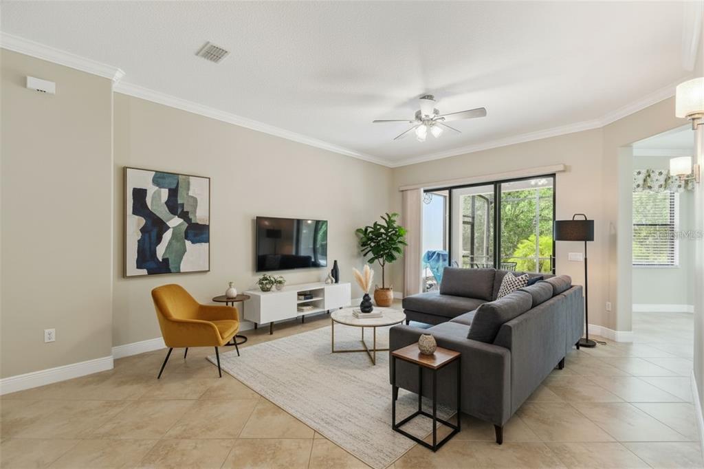 A living room features a gray sectional sofa, a yellow armchair, and a television console — 429 VILLA PARK ROAD, KISSIMMEE, FL