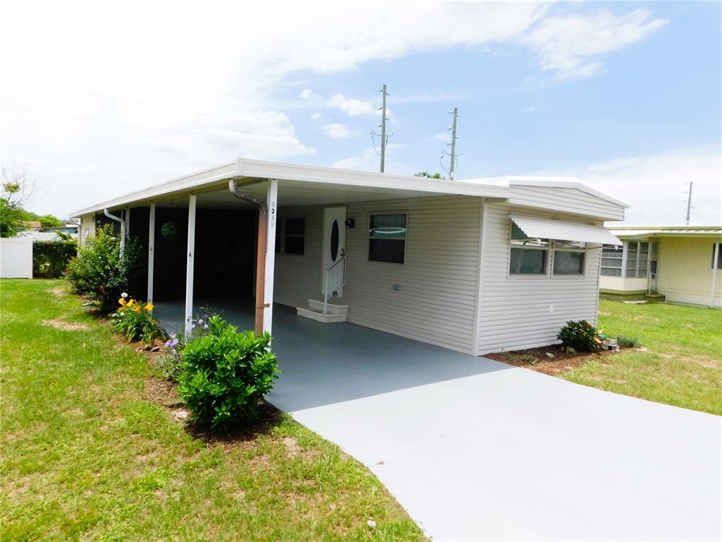 A single-story mobile home with a carport, light siding, and a concrete driveway — 5315 ANTIGUA DRIVE, ZEPHYRHILLS, FL