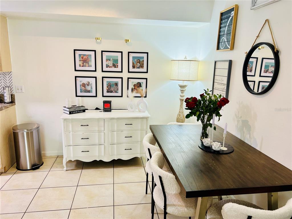 A dining room features a dark wood table, white dresser, and framed wall art — 737 CREST PINES DRIVE UNIT 612, ORLANDO, FL
