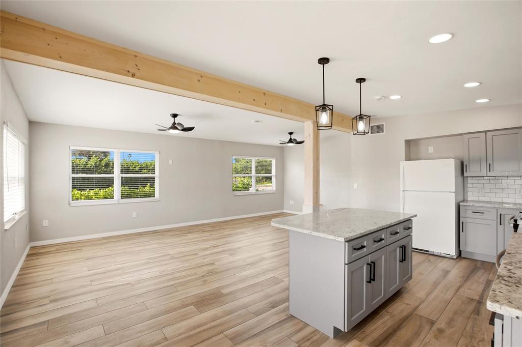 An open-concept kitchen and living area features a wooden support beam, island, and light flooring — 3927 VASCO STREET, PUNTA GORDA, FL