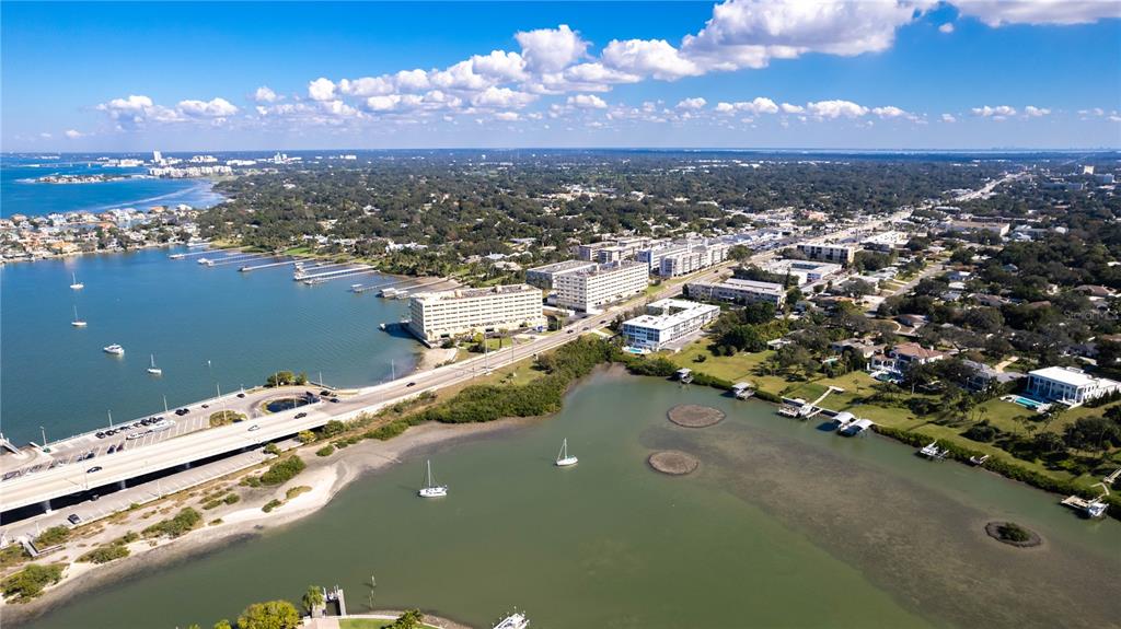 An aerial view shows a bridge, coastal buildings, and boats in a bay — 50 HARBOR VIEW LANE UNIT 11, BELLEAIR BLUFFS, FL