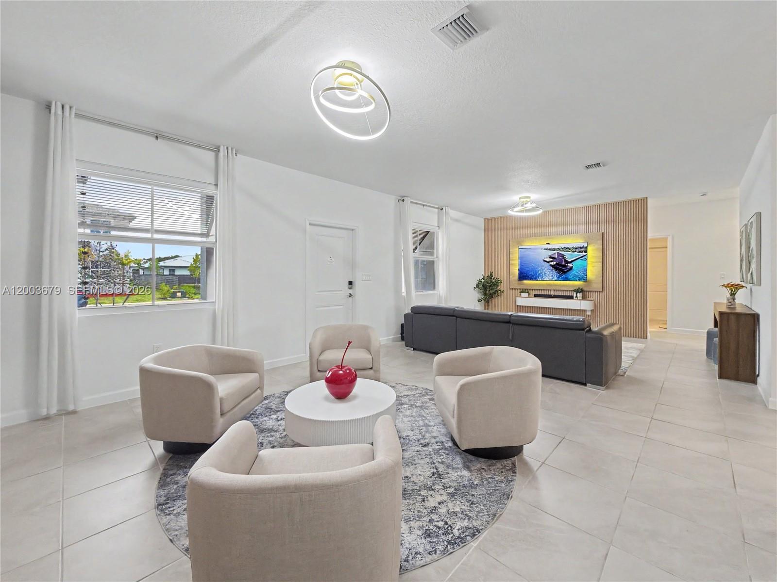 A living room features four beige armchairs, a circular rug, and a wood-slatted accent wall — 13218 SW 189th Ter, Miami FL 33177, MIAMI, FL