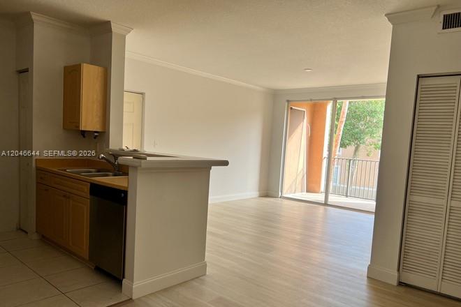 A kitchen with light wood cabinets and a breakfast bar opens into a living area — 6841 SW 44th St # 204, Miami FL 33155, MIAMI, FL