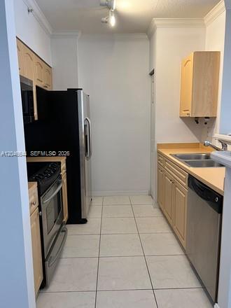 A galley kitchen features light wood cabinets, stainless steel appliances, and white tile flooring — 6841 SW 44th St # 204, Miami FL 33155, MIAMI, FL