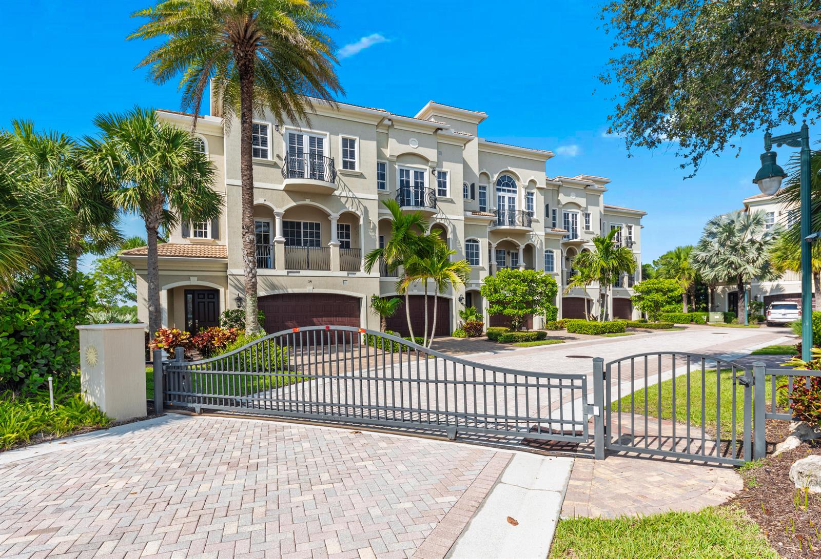 A gated entrance leads to a multi-story residential building with balconies and palm trees — 144 Tierra Lane # 10, Jupiter FL 33477, JUPITER, FL