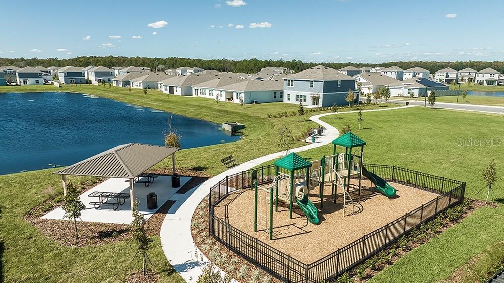 An aerial view of a fenced playground and covered picnic pavilion beside a pond — 5485 ISLA SAONA DRIVE, KISSIMMEE, FL