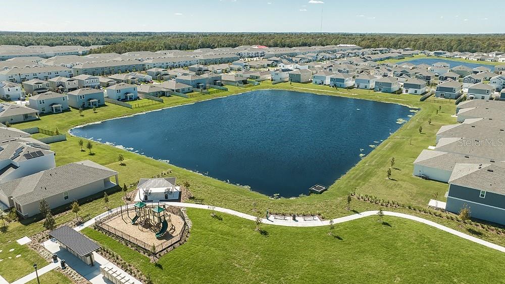 An aerial view shows a neighborhood pond surrounded by houses, a playground, and walking paths — 5485 ISLA SAONA DRIVE, KISSIMMEE, FL