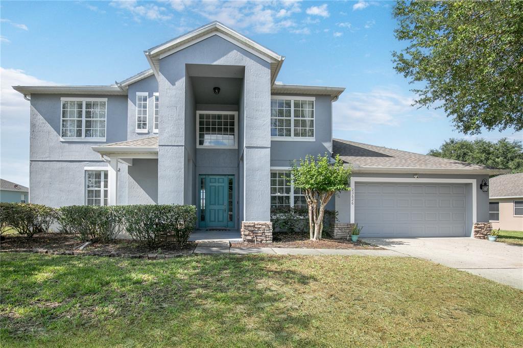 A two-story gray house with a stone-accented entryway and an attached two-car garage — 23626 VALDERAMA LANE, SORRENTO, FL