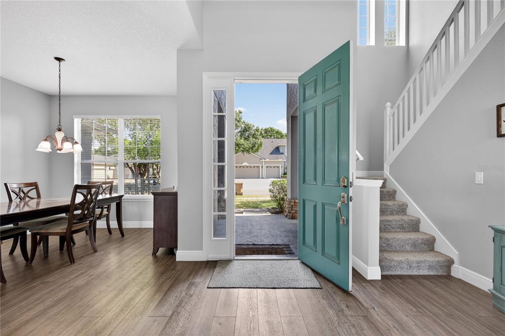 An entryway with wood-look flooring, a teal front door, and a staircase with carpeted steps — 23626 VALDERAMA LANE, SORRENTO, FL