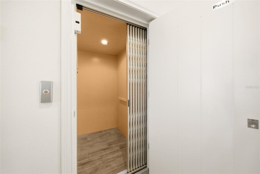 An elevator with a folding metal gate sits behind an open white door — 8017 SURF STREET, KISSIMMEE, FL