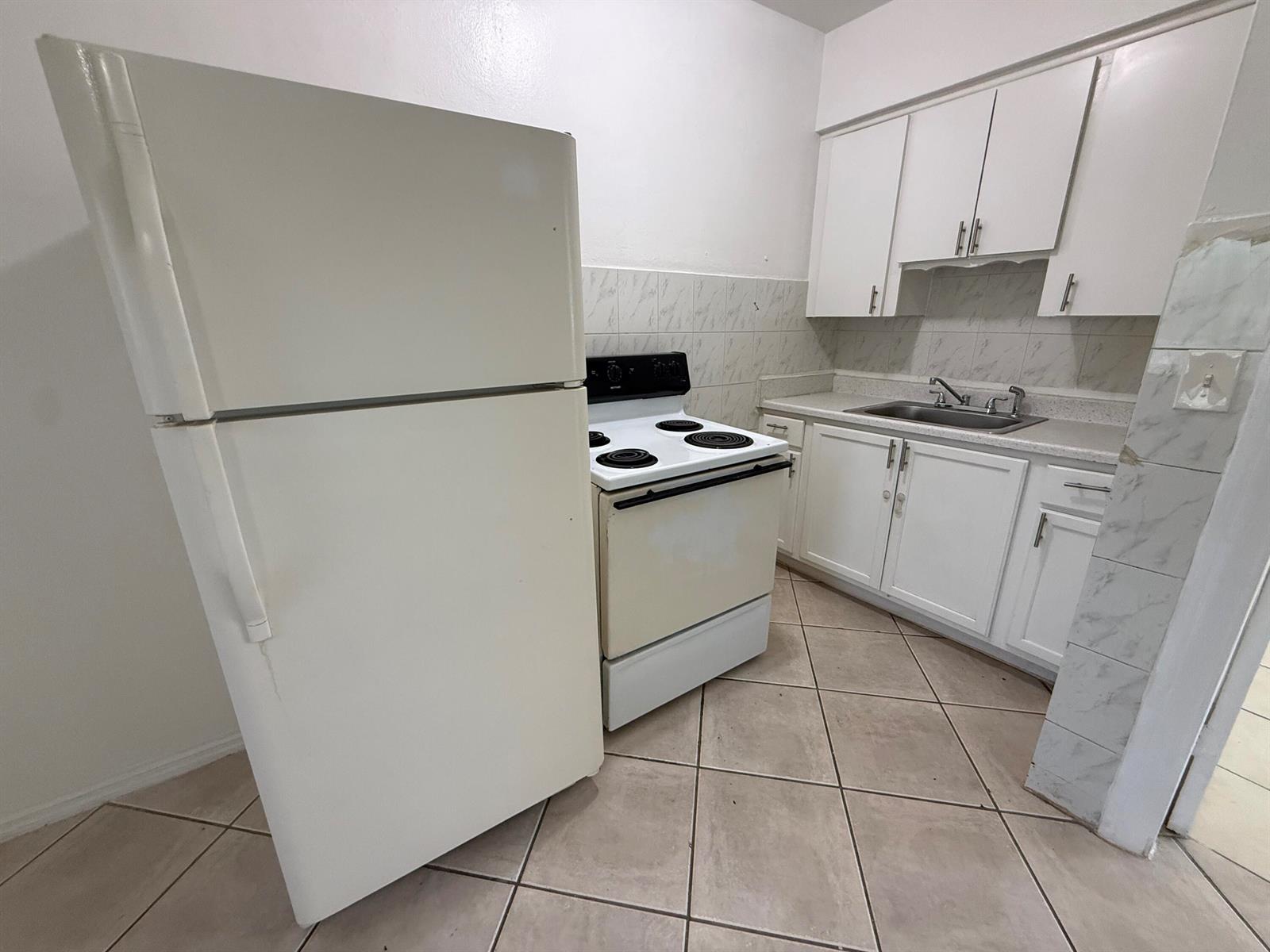 A kitchen features white cabinets, a white refrigerator, a white stove, and tiled flooring — 6014 Fillmore Street # 4e, Hollywood FL 33024, HOLLYWOOD, FL