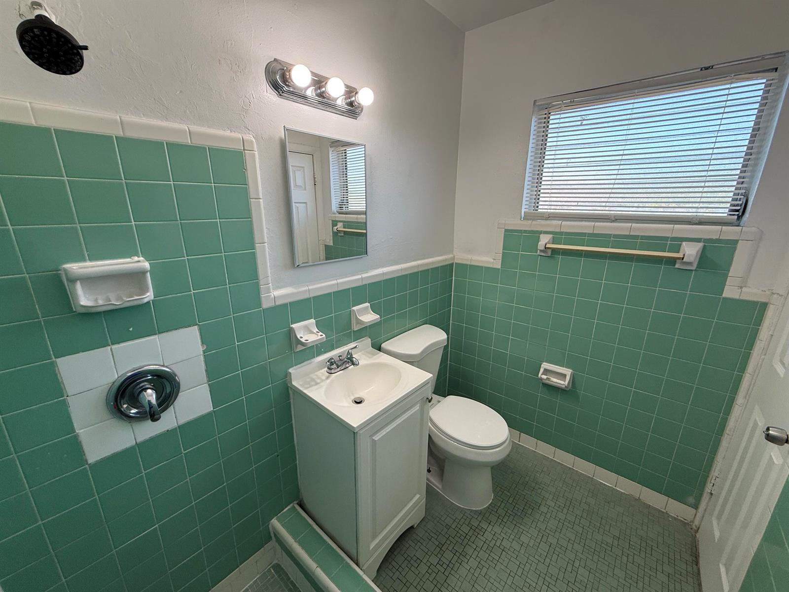 A bathroom features green wall tiles, a white pedestal sink, a toilet, and a shower — 6014 Fillmore Street # 4e, Hollywood FL 33024, HOLLYWOOD, FL