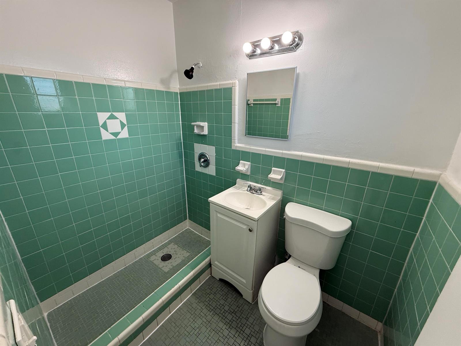 A small bathroom features green tiled walls, a shower stall, a pedestal sink, and toilet — 6014 Fillmore Street # 4e, Hollywood FL 33024, HOLLYWOOD, FL