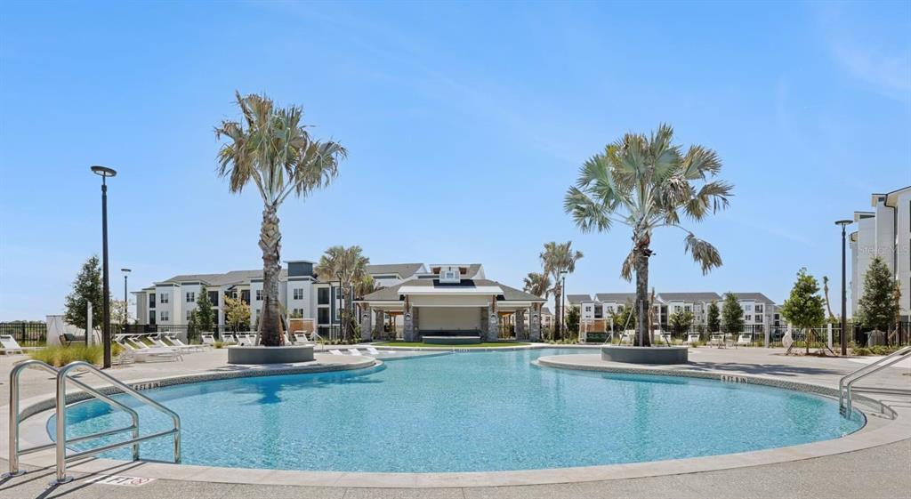 A swimming pool with palm trees and a covered pavilion sits in front of apartment buildings — 1305 FARKLEBERRY LANE UNIT A2, DAVENPORT, FL
