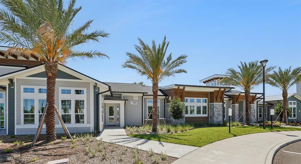 The exterior of a modern building features gray siding, stone accents, and several palm trees — 1305 FARKLEBERRY LANE UNIT A2, DAVENPORT, FL