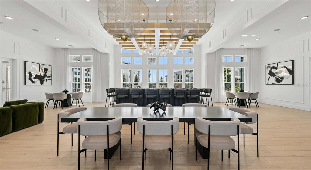 A spacious, modern room features a large dining table, a bar area, and two large chandeliers — 1305 FARKLEBERRY LANE UNIT A2, DAVENPORT, FL