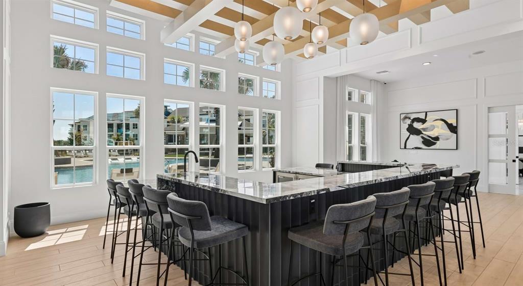 A modern bar area features a large marble-topped island with dark vertical paneling and stools — 1305 FARKLEBERRY LANE UNIT A2, DAVENPORT, FL