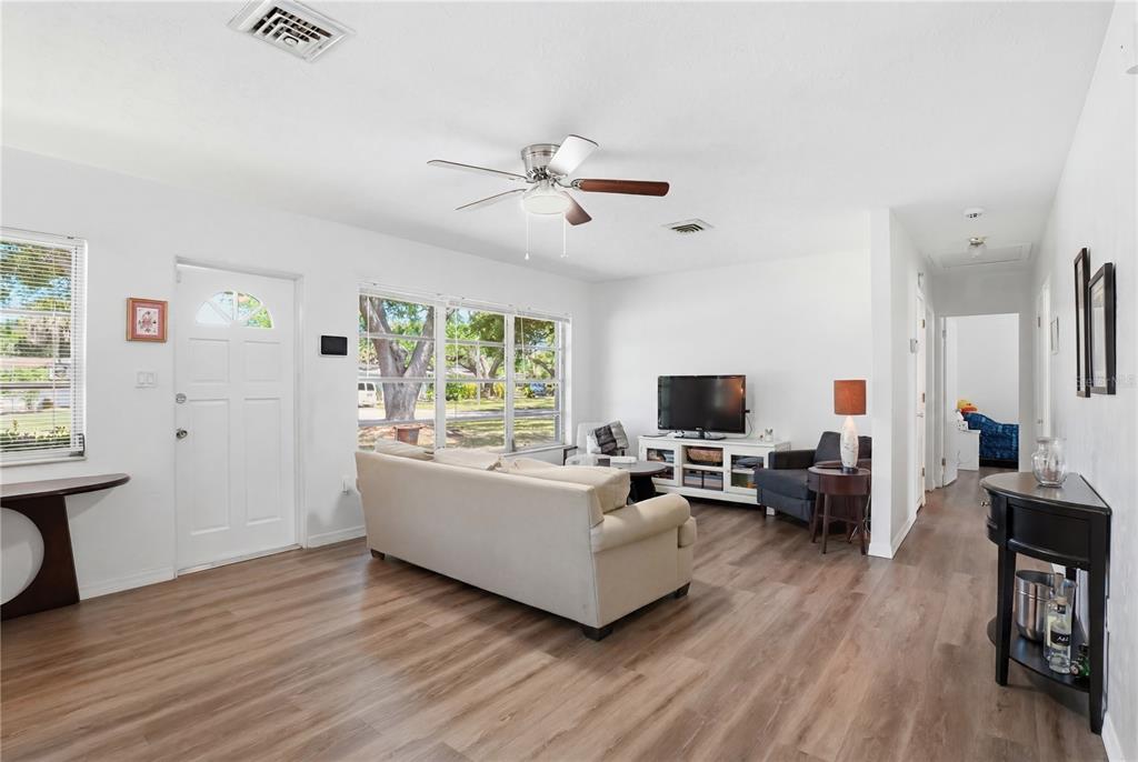 A living room with white walls, wood-look flooring, a ceiling fan, and a beige sofa — 73 SAINT LUCIE AVENUE, SARASOTA, FL