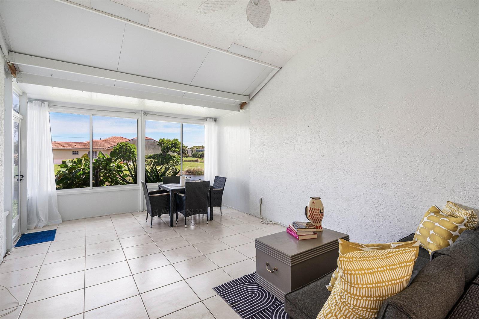 A sunroom features tile flooring, a dining set, a sofa, and large windows overlooking outdoors — 6192 Floral Lakes Drive, Delray Beach FL 33484, DELRAY BEACH, FL