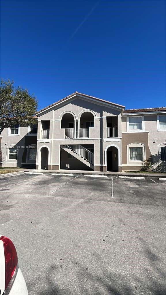 A two-story apartment building exterior features arched balconies, a staircase, and a parking lot — 2811 SE 17th Ave # 210, Homestead FL 33035, HOMESTEAD, FL