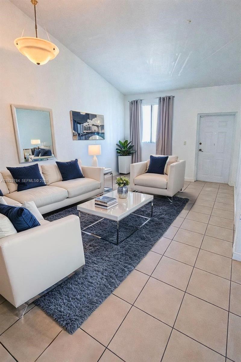 A living room features white sofas, a coffee table, and a dark rug on tile floors — 2811 SE 17th Ave # 210, Homestead FL 33035, HOMESTEAD, FL