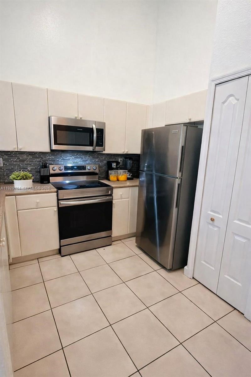 A kitchen features white cabinets, stainless steel appliances, and light-colored tile flooring — 2811 SE 17th Ave # 210, Homestead FL 33035, HOMESTEAD, FL