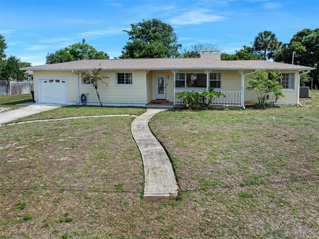 A single-story, light yellow house with a white garage door and a front walkway — 307 MANHATTAN AVENUE, DAYTONA BEACH, FL