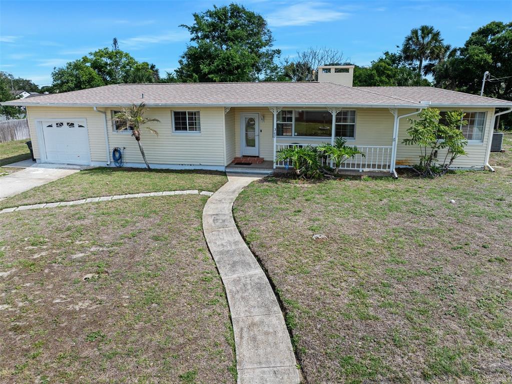 A single-story yellow house with a white garage, front porch, and a concrete walkway — 307 MANHATTAN AVENUE, DAYTONA BEACH, FL