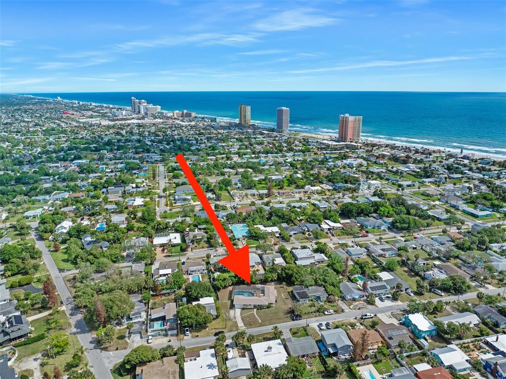 An aerial view shows a residential neighborhood with a house highlighted by a red arrow — 307 MANHATTAN AVENUE, DAYTONA BEACH, FL