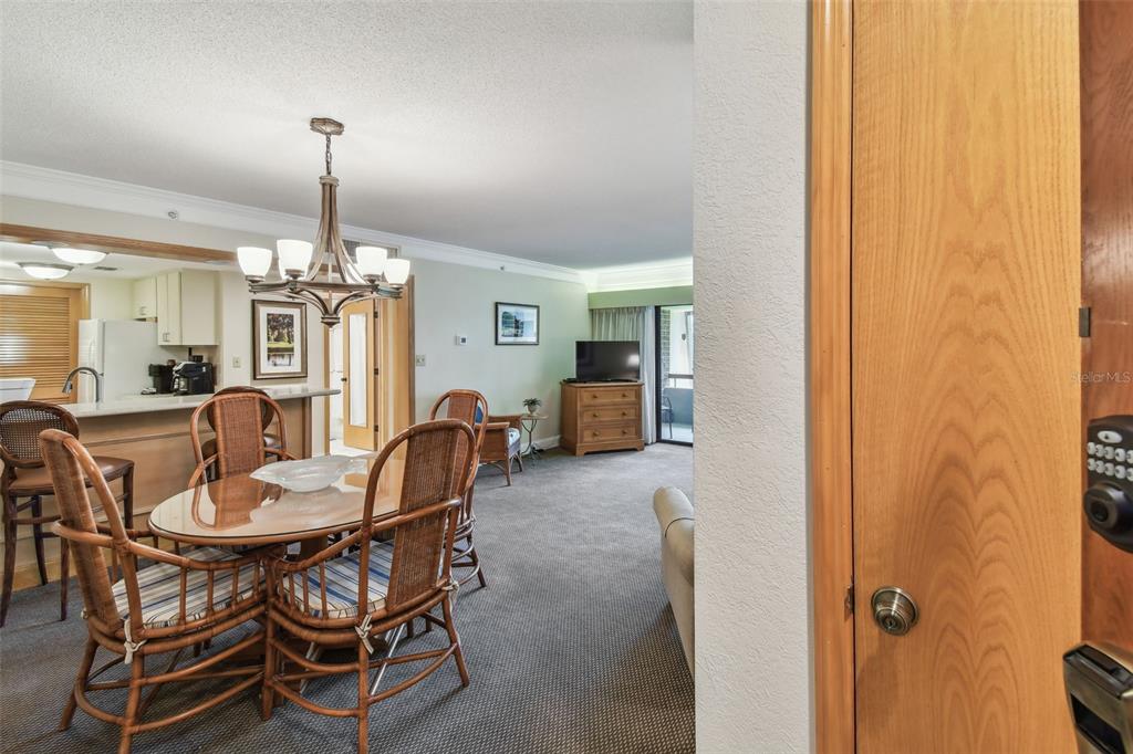 A dining area with a wicker table set sits adjacent to a living room space — 36750 US 19 N UNIT 15309, PALM HARBOR, FL