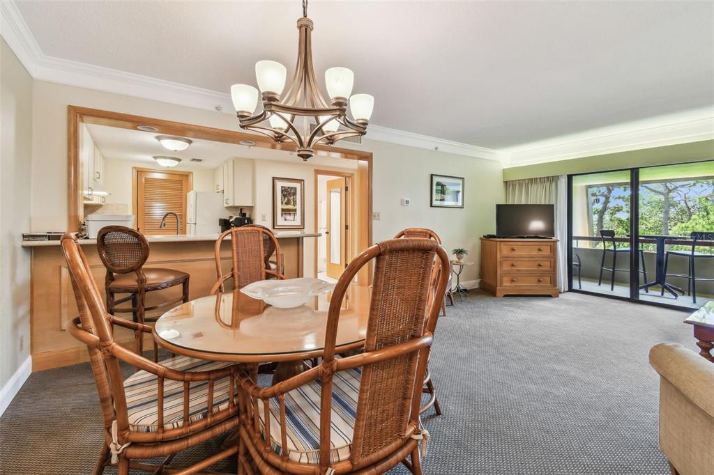 A dining area with a glass table and wicker chairs sits before an open kitchen — 36750 US 19 N UNIT 15309, PALM HARBOR, FL