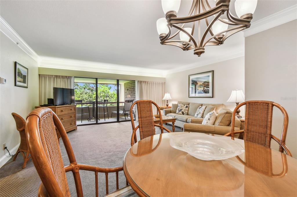 A living and dining area features wicker chairs, a glass-topped table, and a sliding glass door — 36750 US 19 N UNIT 15309, PALM HARBOR, FL