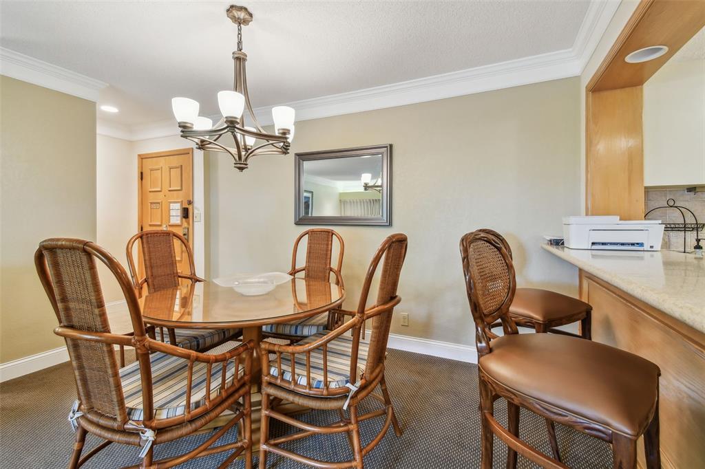 A dining area features a glass-topped table with wicker chairs and a breakfast bar — 36750 US 19 N UNIT 15309, PALM HARBOR, FL