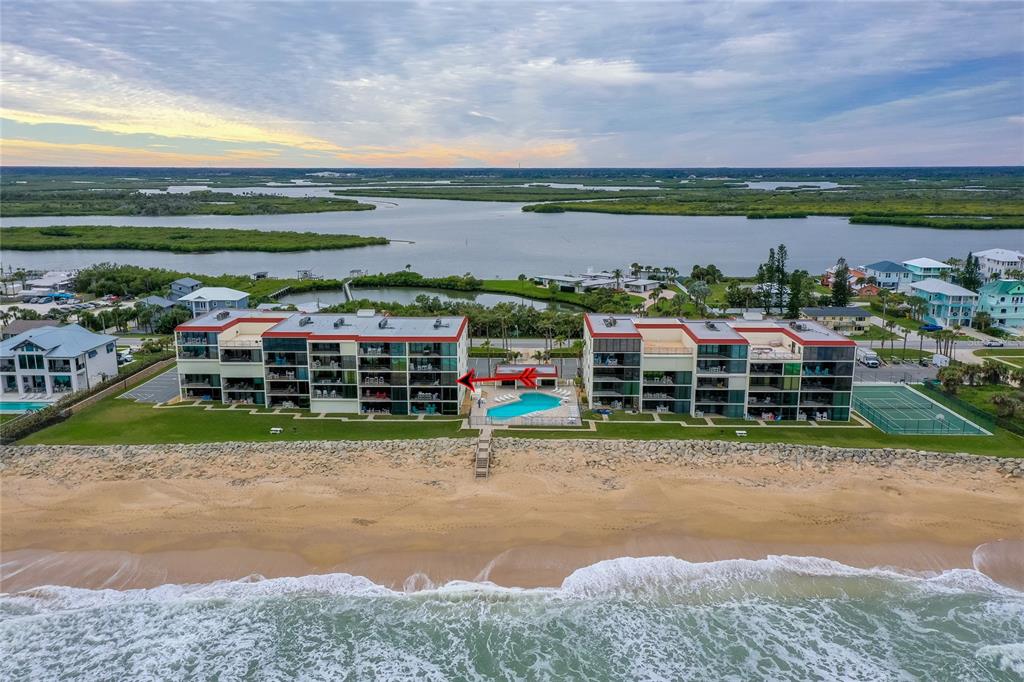 An aerial view of two beachfront condominium buildings with a swimming pool and tennis court — 6727 TURTLEMOUND ROAD UNIT 315, NEW SMYRNA BEACH, FL