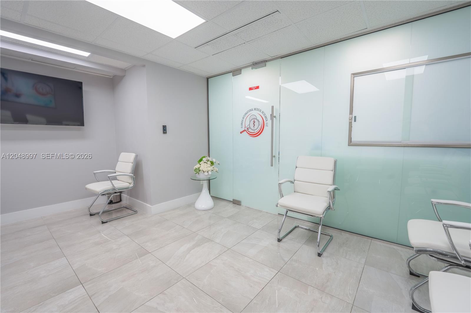 A waiting room features white chairs, tile flooring, and a glass door with a logo — 747 Ponce De Leon Blvd # 402, Coral Gables FL 33134, CORAL GABLES, FL