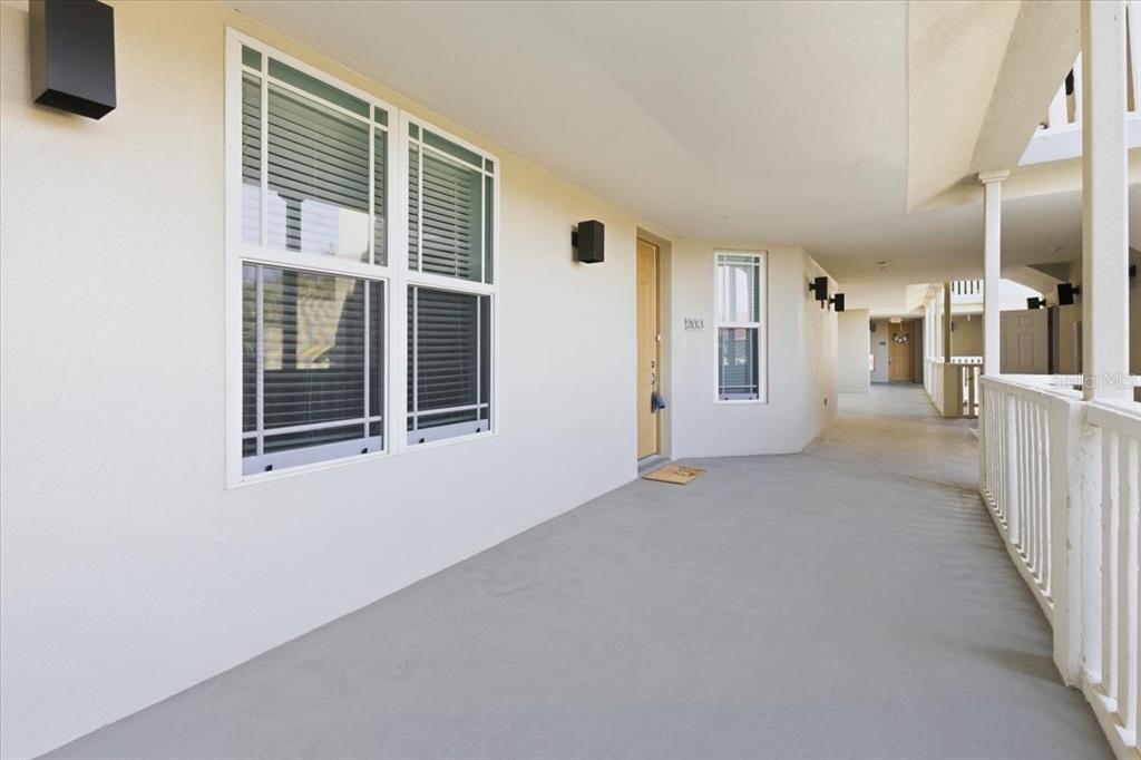 An exterior view of a covered apartment building walkway featuring a unit entrance door — 10045 LINKS LANE UNIT 203, ROTONDA WEST, FL