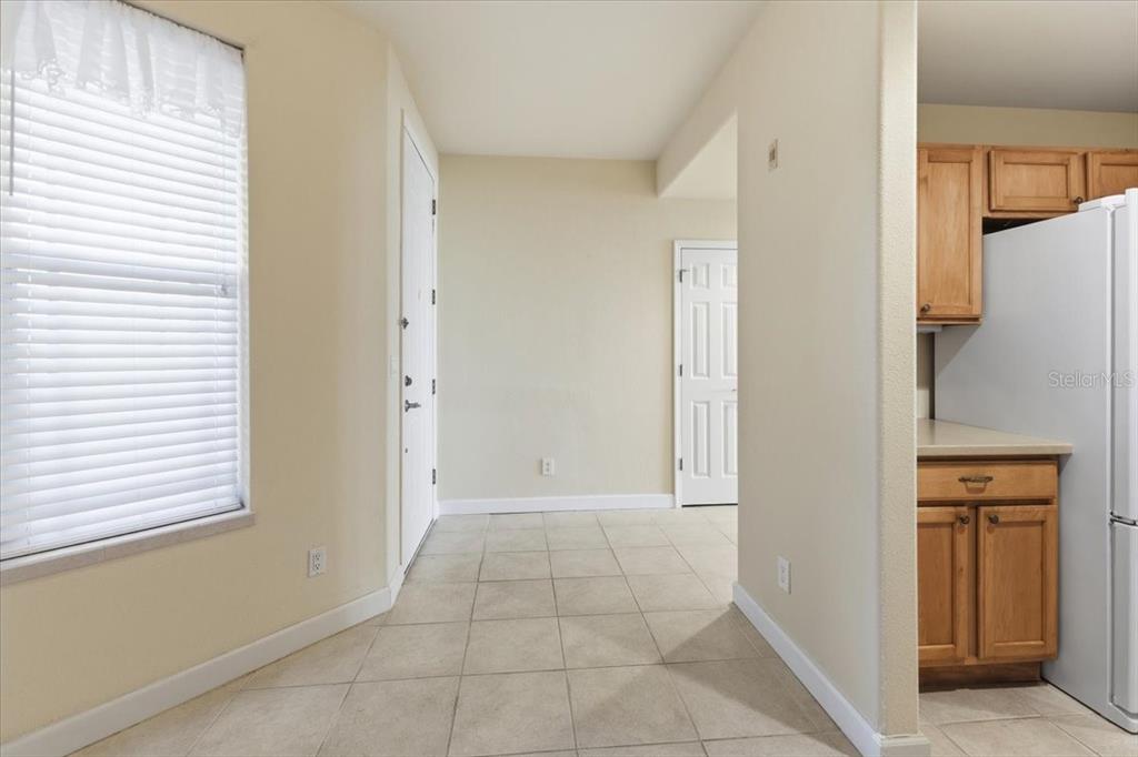 A tiled kitchen area features light-colored walls, a window with blinds, and wooden cabinets — 10045 LINKS LANE UNIT 203, ROTONDA WEST, FL